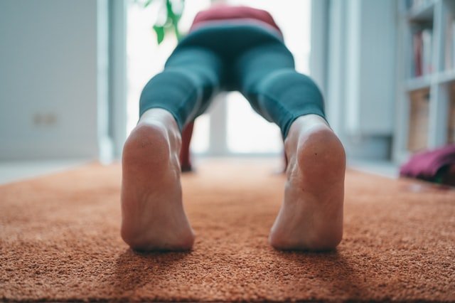Deportista tumbado en el suelo haciendo ejercicios de rehabilitación para el tendón de Aquiles